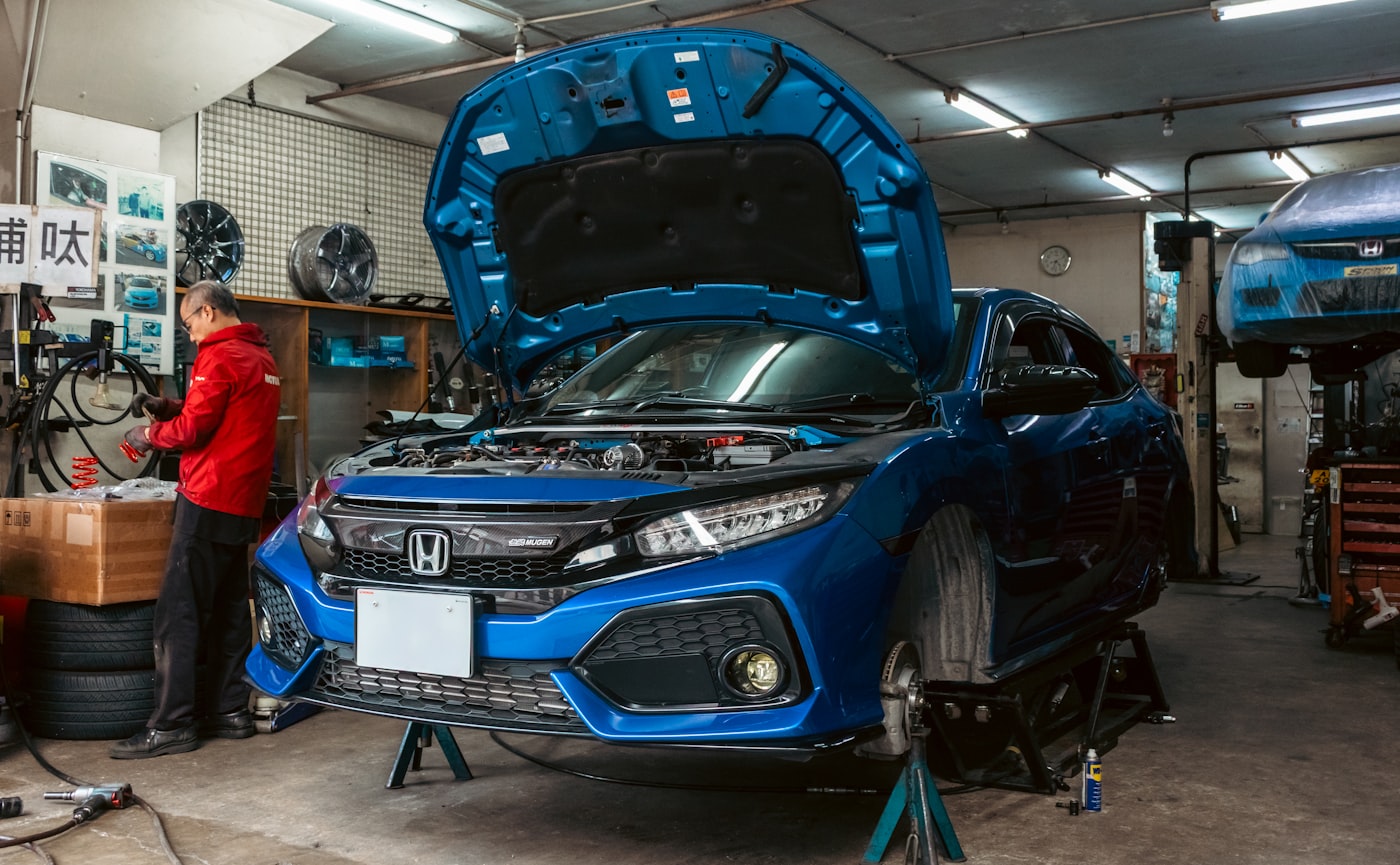 A mechanic working beside a car raised on stands in an independent garage